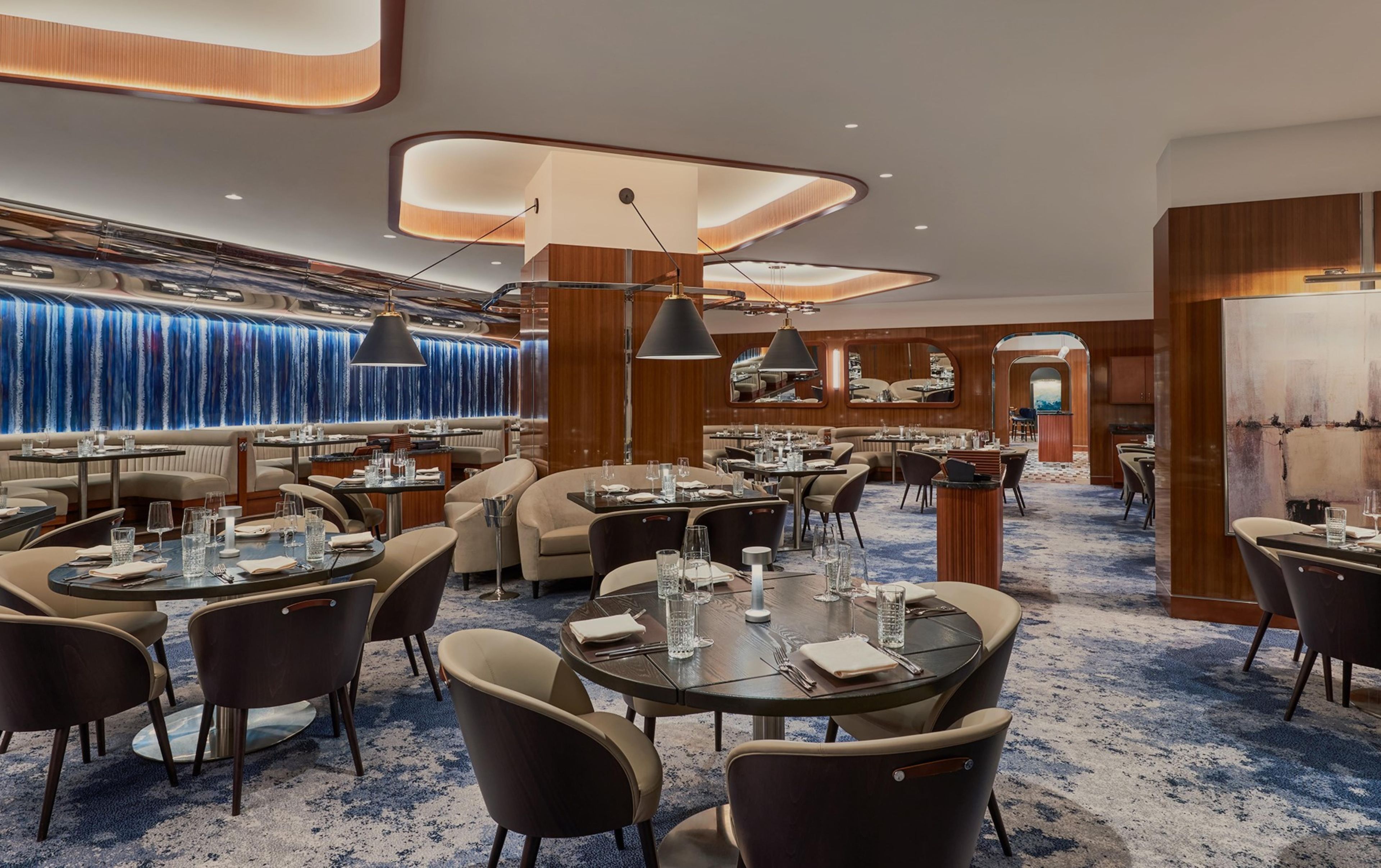 Un espace de restauration moderne avec des tables rondes, des chaises et un éclairage d’ambiance.
