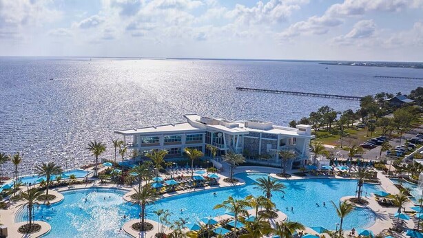 A resort with a large pool, a pier extending into the sea, and a building with a modern design. - Sunsuites Villas At Sunseeker Resort, Curio By Hilton (Charlotte Harbor)