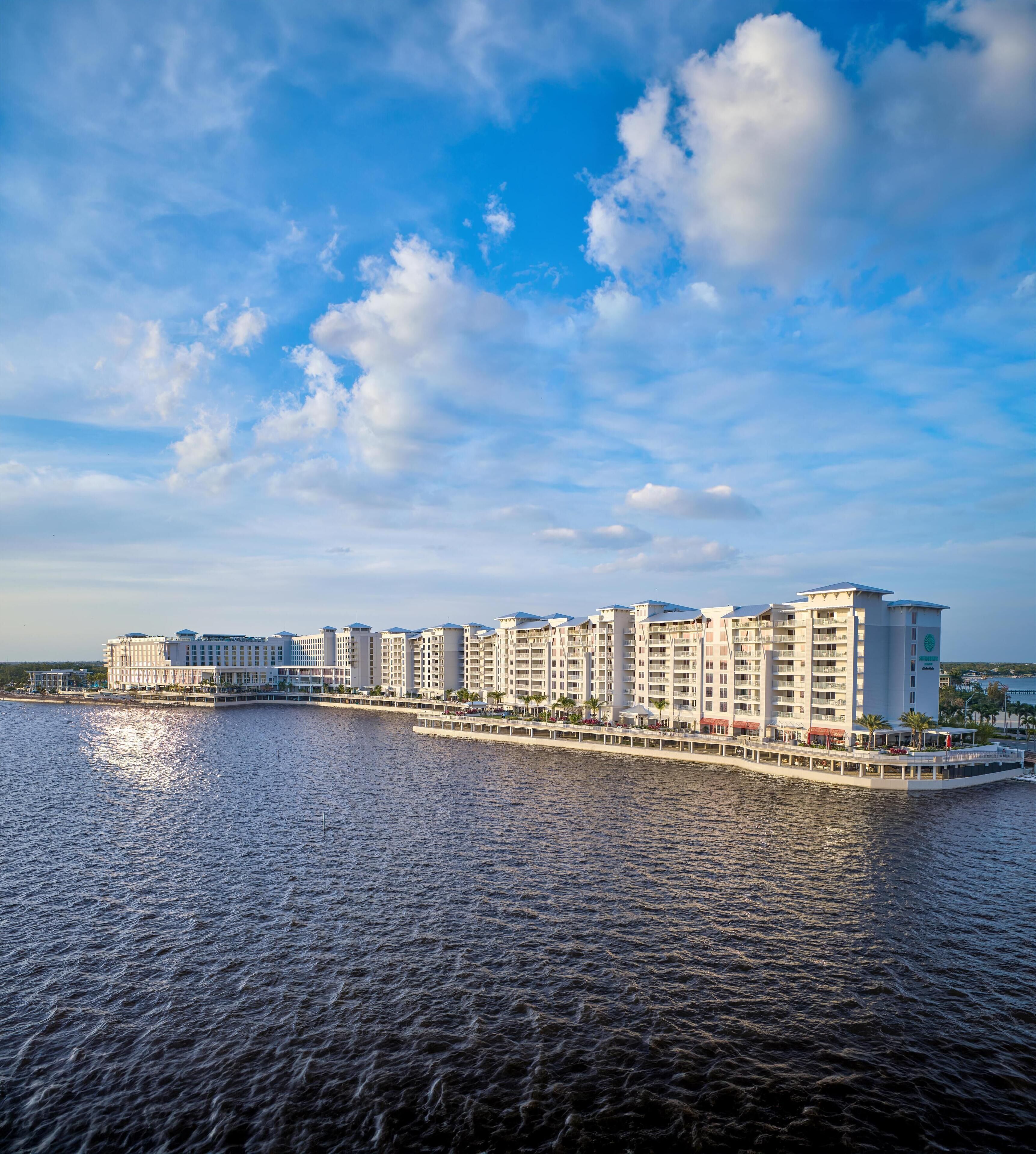 Ein Hotel am Wasser mit mehreren Gebäuden, einem Steg und wolkenlosem Himmel.