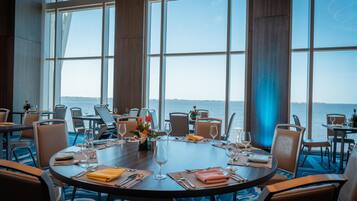 A dining area with round tables, chairs, and a view of the sea.