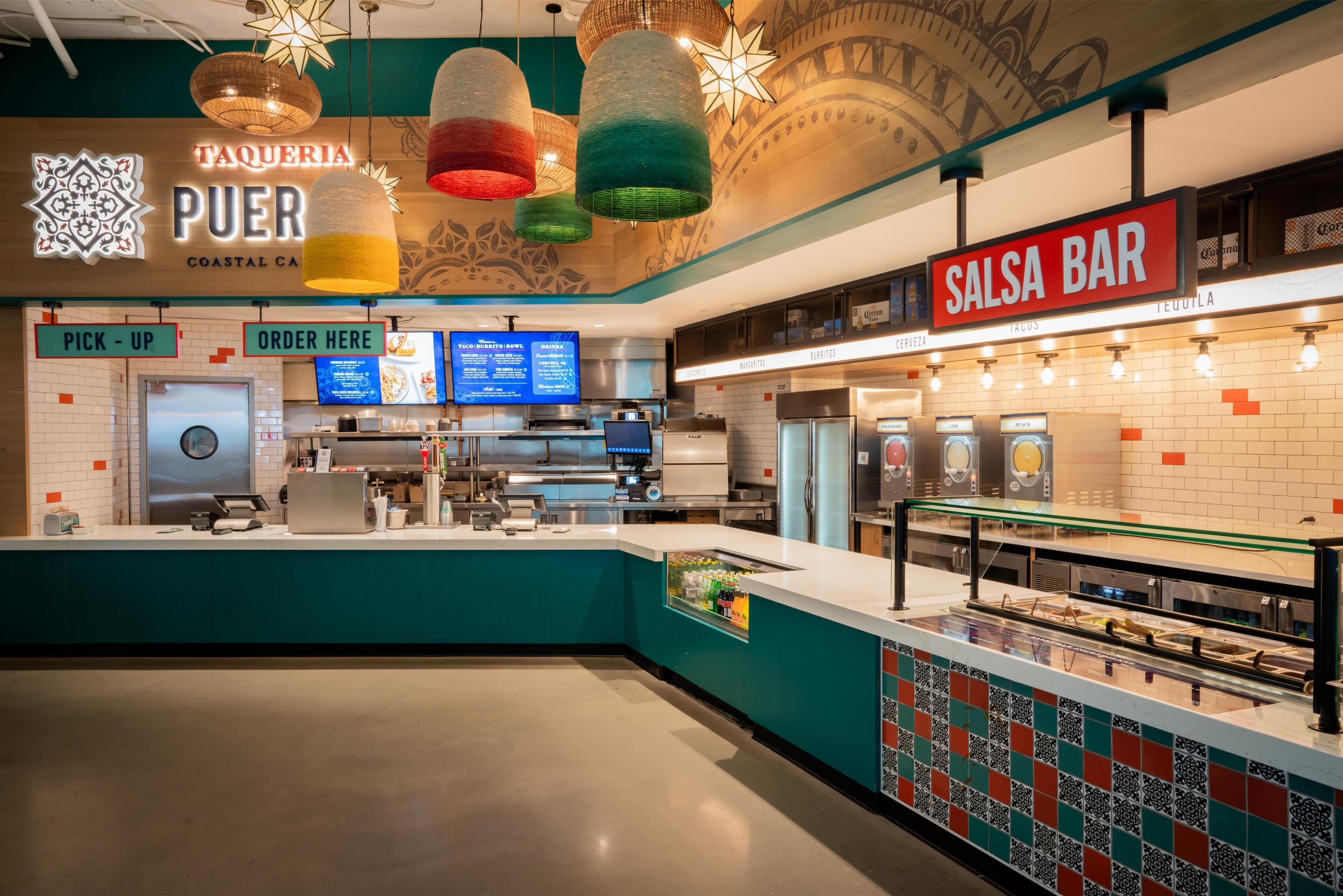 A restaurant interior with a counter, a sign for 'Salsa Bar', and a 'PICK UP' and 'ORDER HERE' sign.