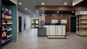 Een hotel receptie met een balie, een aan de muur bevestigde televisie en een plank met snacks.
