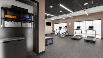 A gym with exercise equipment, a TV, and a clock on the wall.
