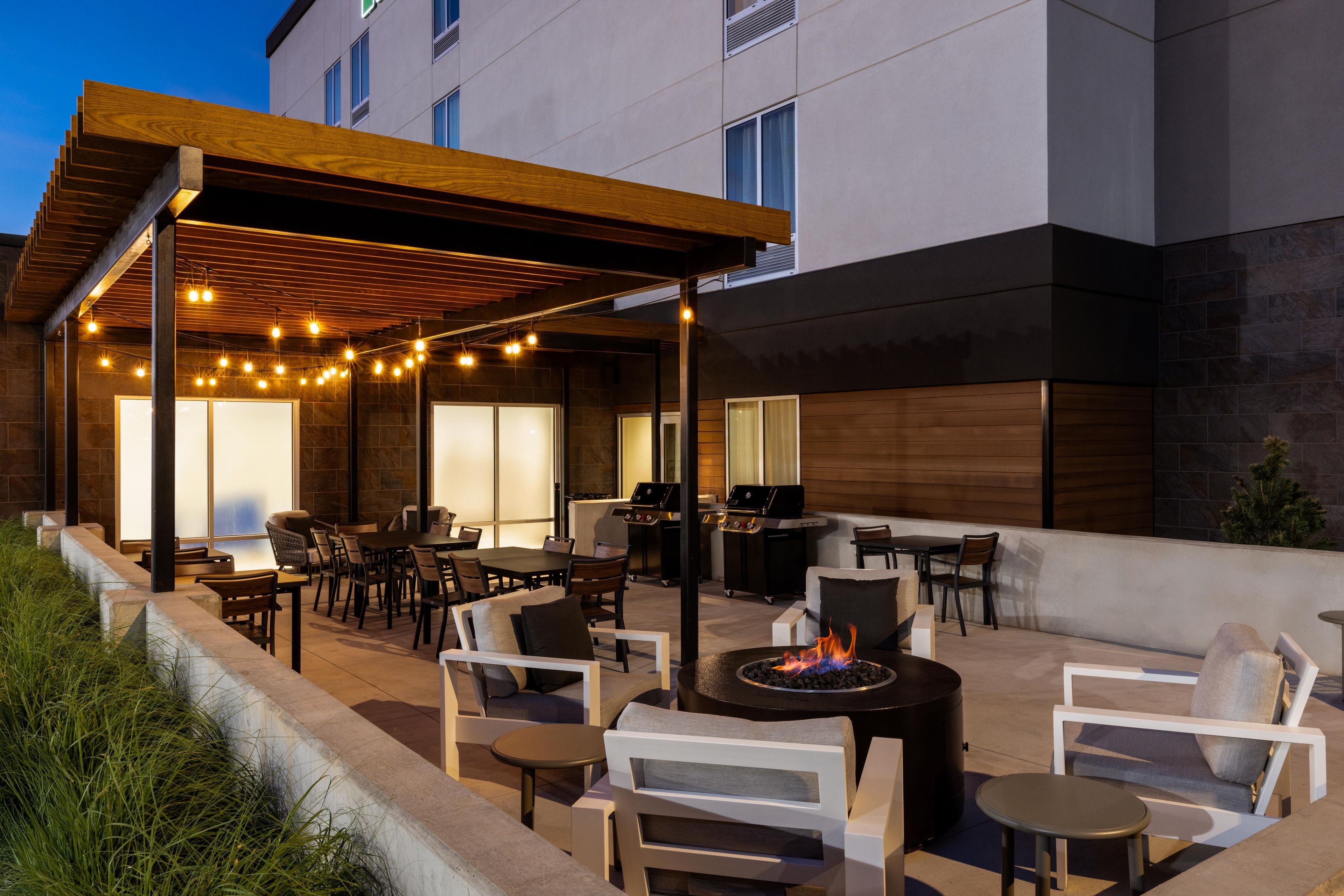 Eine Außenpatio-Terrasse mit Sitzgelegenheiten, einem Grill und Lichterketten.