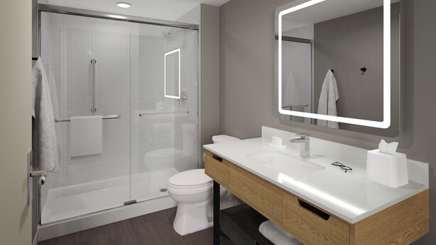 A modern bathroom with a glass-enclosed shower, a white toilet, and a vanity with a mirror. - LivSmart Studios by Hilton Salt Lake City West Valley City (West Valley City)