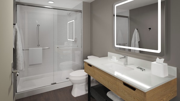 Une salle de bain moderne avec une douche à parois de verre, des toilettes blanches et un meuble-lavabo avec un miroir.
