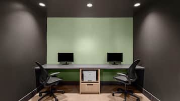 A conference room with two desks, each with a monitor, chairs, and a printer.