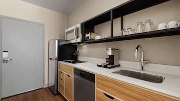 Una cocina compacta equipada con lavavajillas, cafetera y microondas.