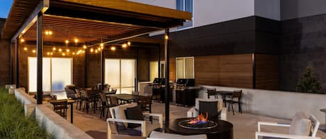An outdoor patio area with seating, a grill, and string lights.