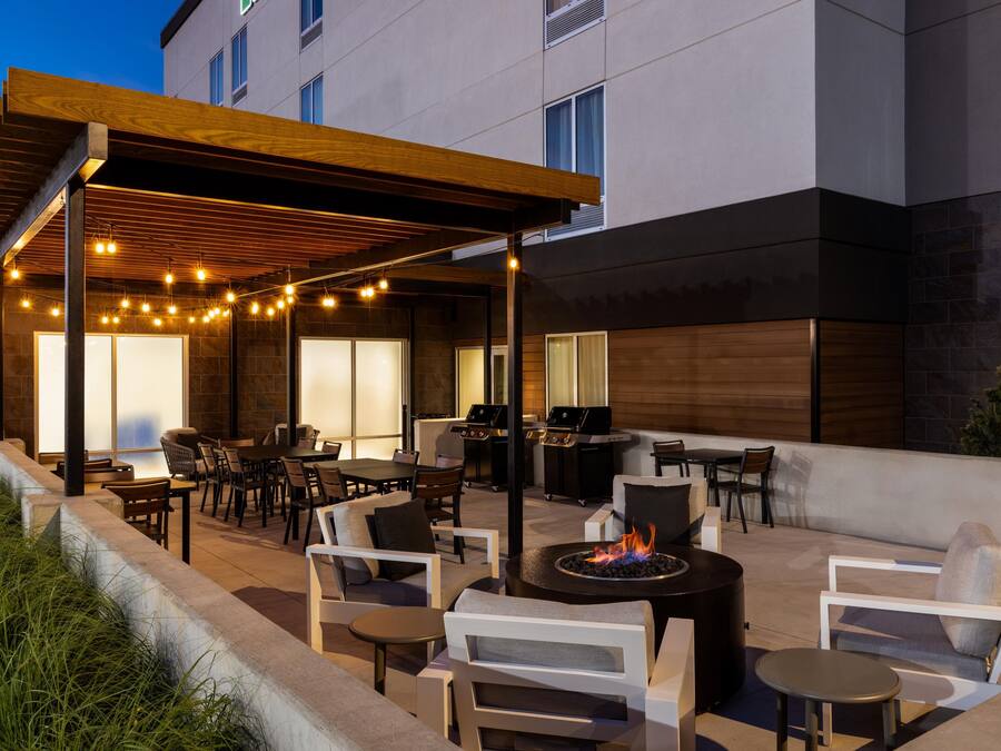An outdoor patio area with seating, a grill, and string lights.