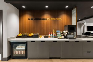Una estación de café moderna con una pared de madera, un refrigerador y una máquina de café.