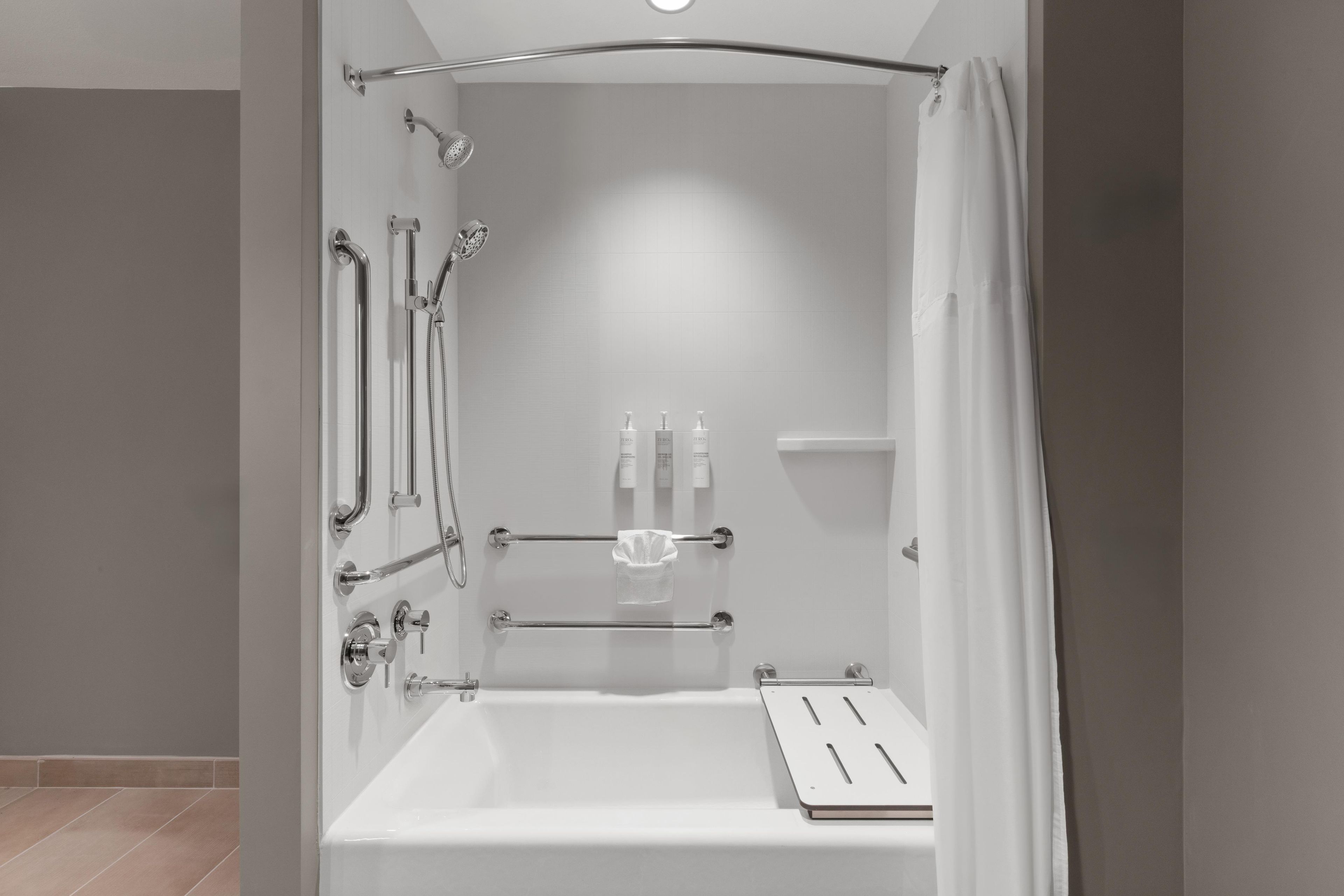 A modern shower with a handheld showerhead, a handheld shower attachment, and a handheld scrubber.