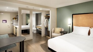 Een hotelkamer met een bed, bureau, stoel, kast en badkamer.
