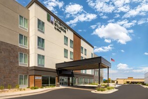 A hotel with a modern facade, a covered entrance, and an American flag.