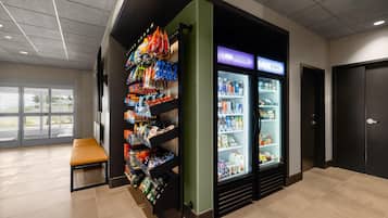 A vending area with snacks and drinks, a seating bench, and a refrigerated section labeled 'COOL QUENCHERS' and 'DELIGHTS'.