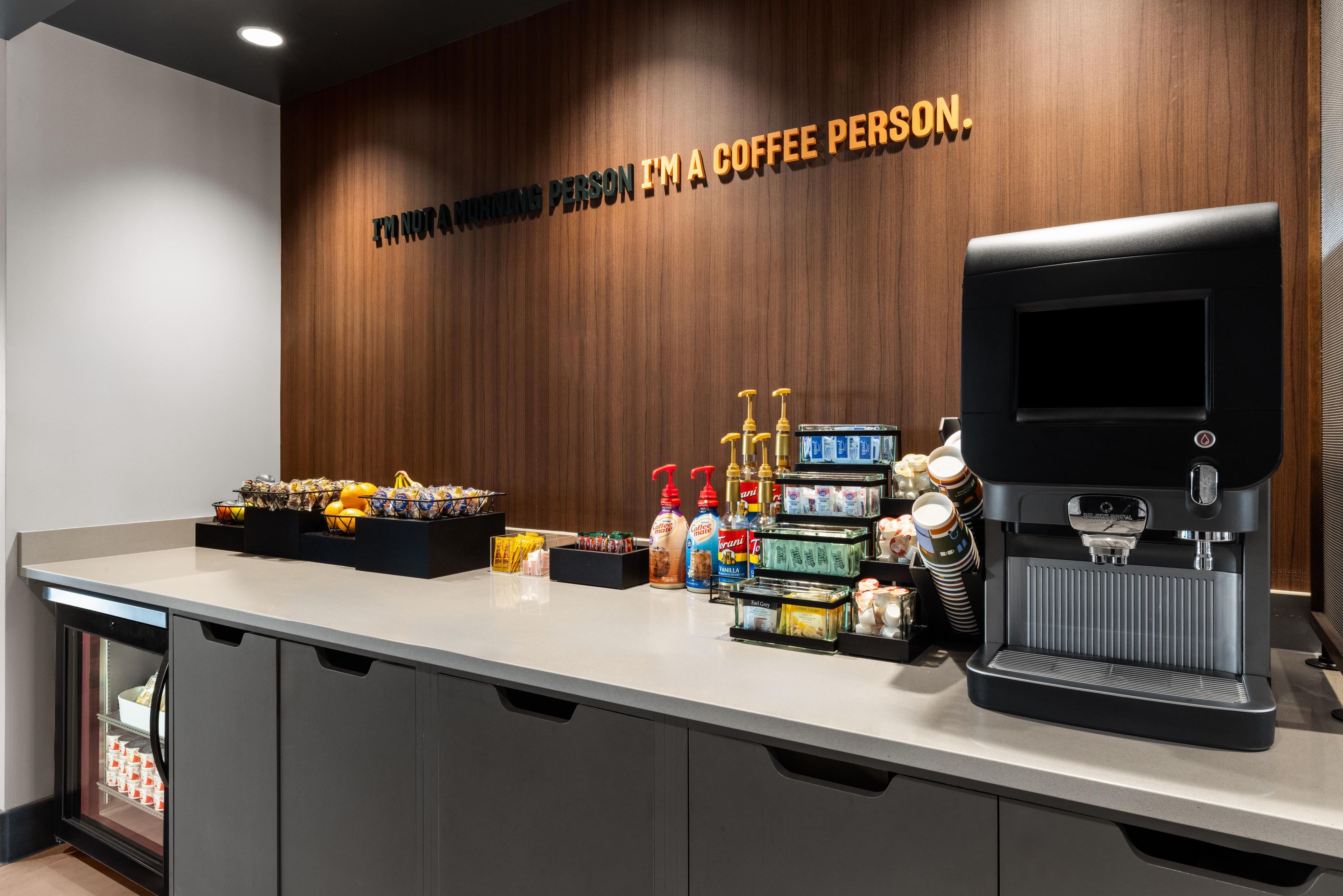 A coffee station with a coffee machine, various coffee pods, and a selection of snacks.