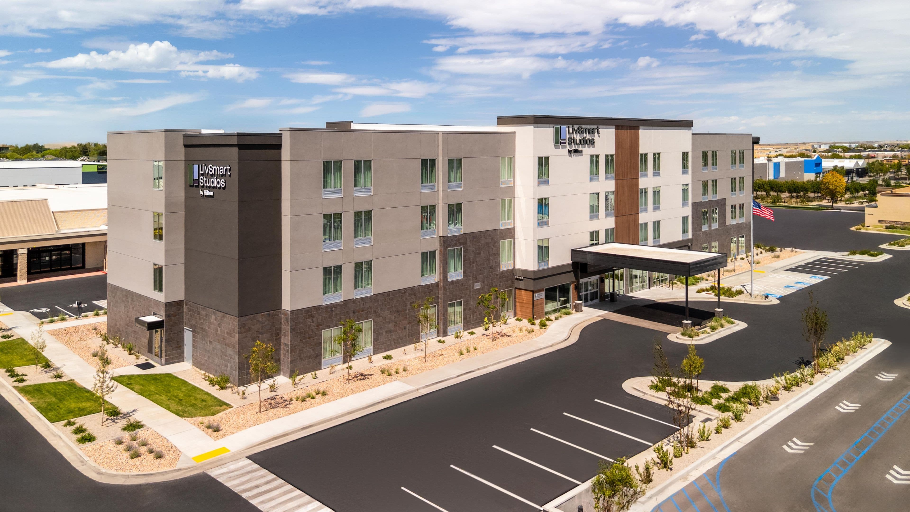 A modern hotel building with a flat roof, multiple windows, and a covered entrance.