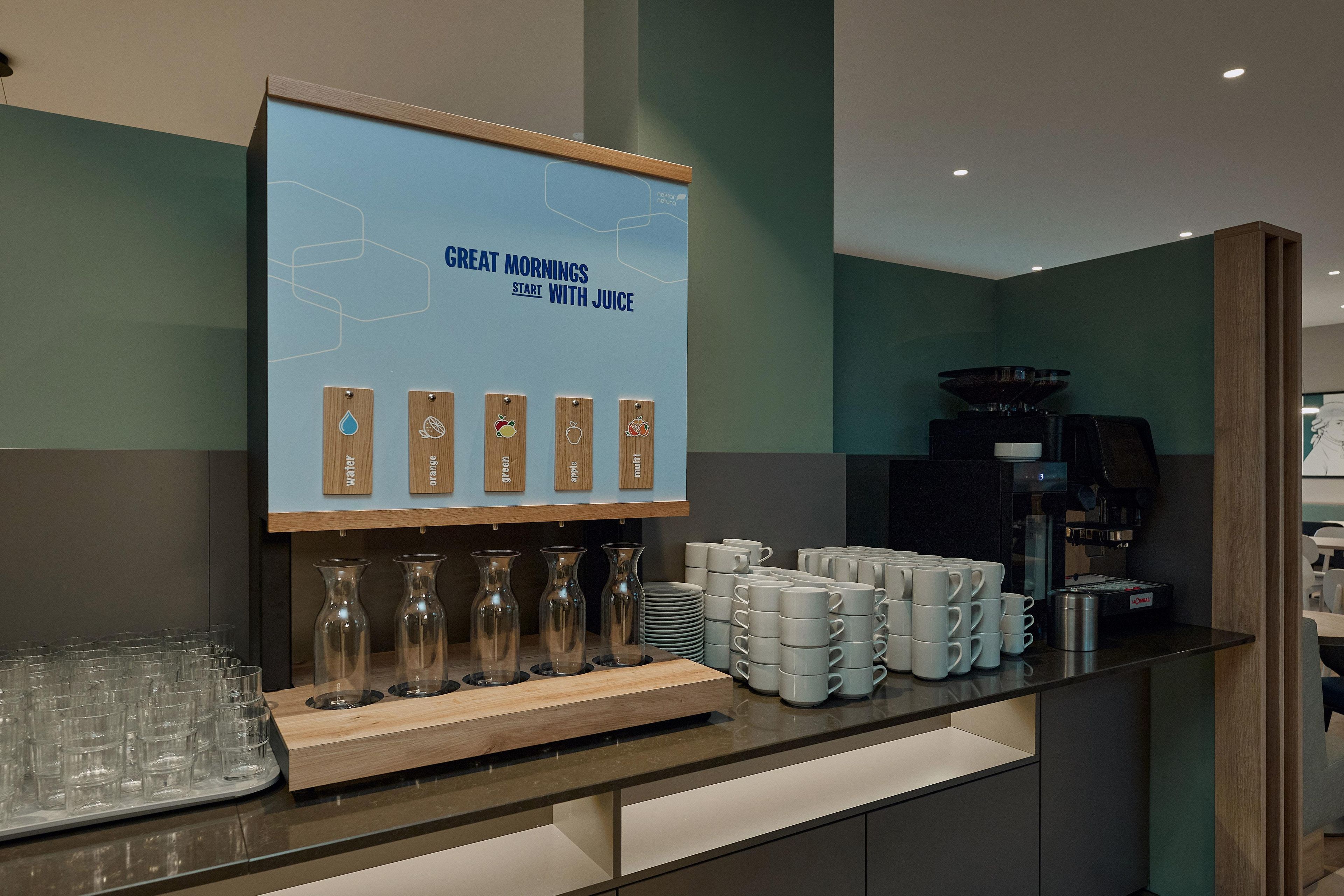 Una barra de desayuno con un letrero que dice 'GREAT MORNINGS START WITH JUICE' y una variedad de opciones de jugo.