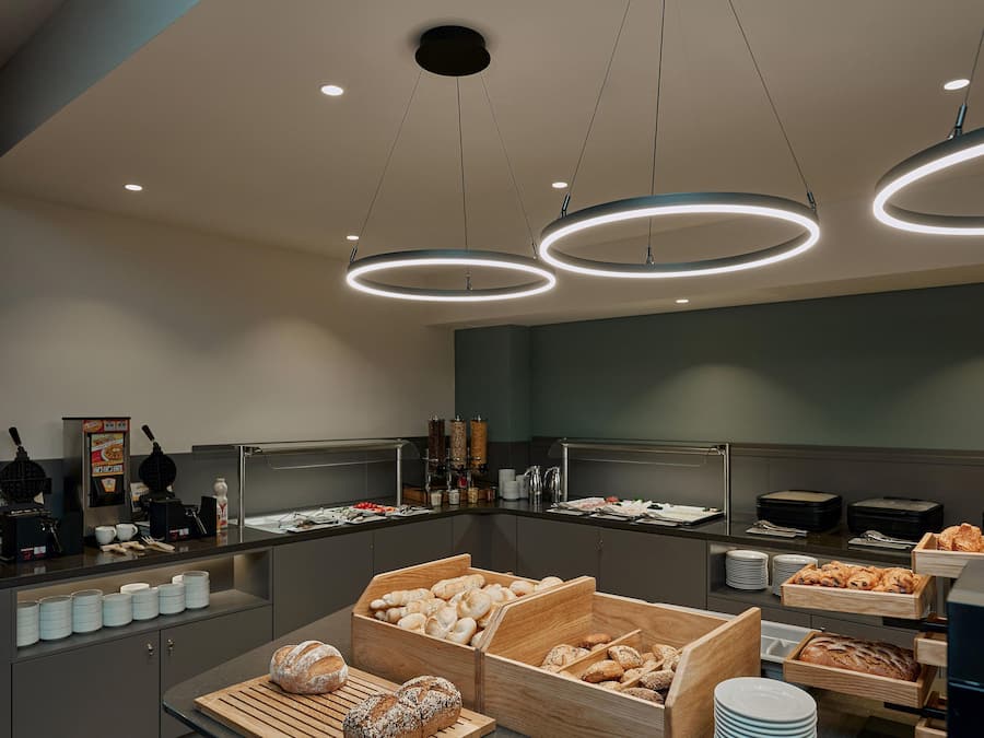 A modern breakfast area with a waffle maker, coffee machine, and various breakfast items.