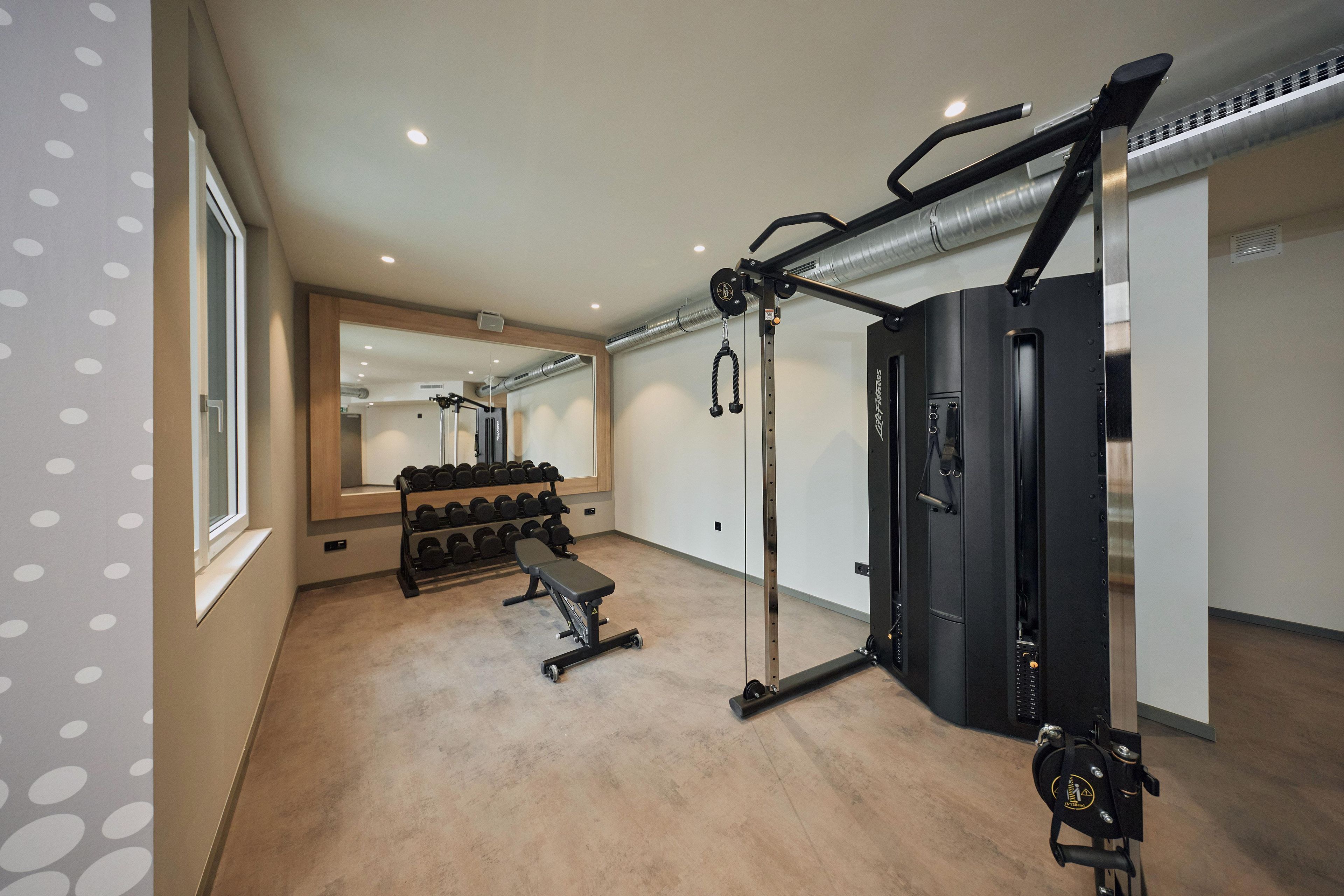 Een fitnessruimte met een bank, een gewichtrek en een squatrek.