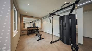 Een fitnessruimte met een bank, een gewichtrek en een squatrek.