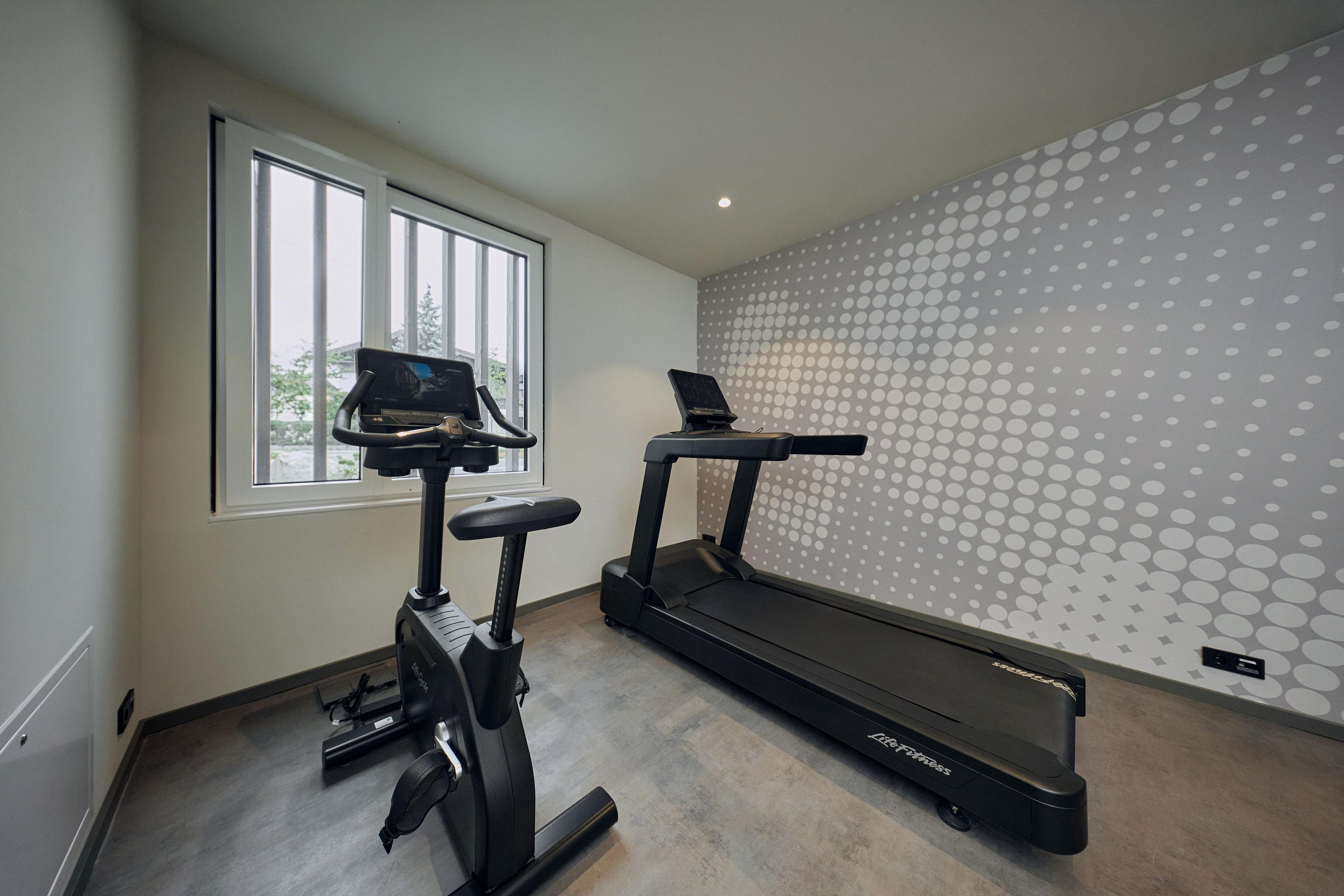 A home gym with a stationary bike, elliptical, and treadmill.