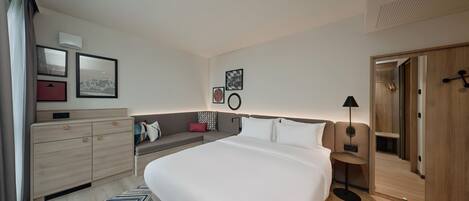 Una habitación de hotel moderna con una cama grande, un sofá, un escritorio y un armario.