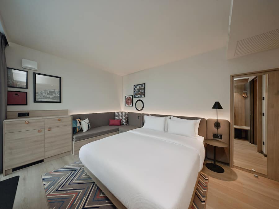 Een moderne hotelkamer met een groot bed, een bank, een bureau en een kledingkast.