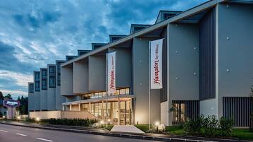 Een modern hotel met een vlakke gevel, grote ramen en een opvallende entree.