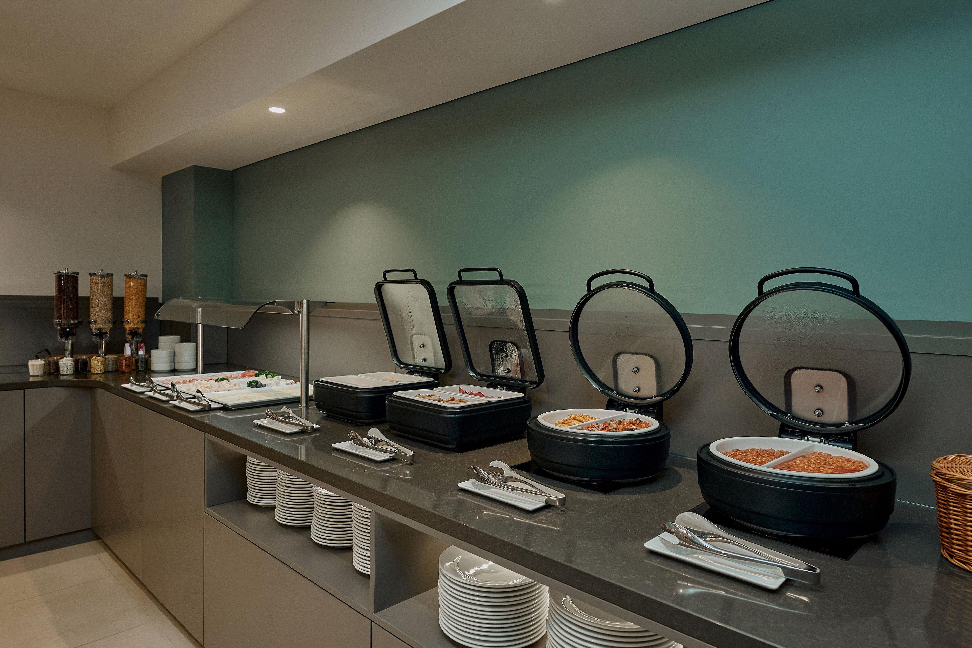 A buffet setup with multiple food containers and serving utensils.