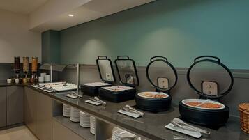 A buffet setup with multiple food containers and serving utensils.