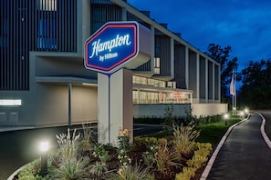 En hotellskylt med namnet ”Hilton Hampton” och en modern byggnad med stora fönster och ett platt tak.