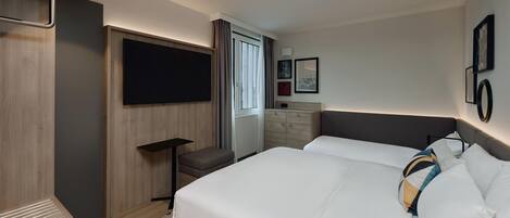 A hotel room with a bed, a TV, a dresser, and a window.