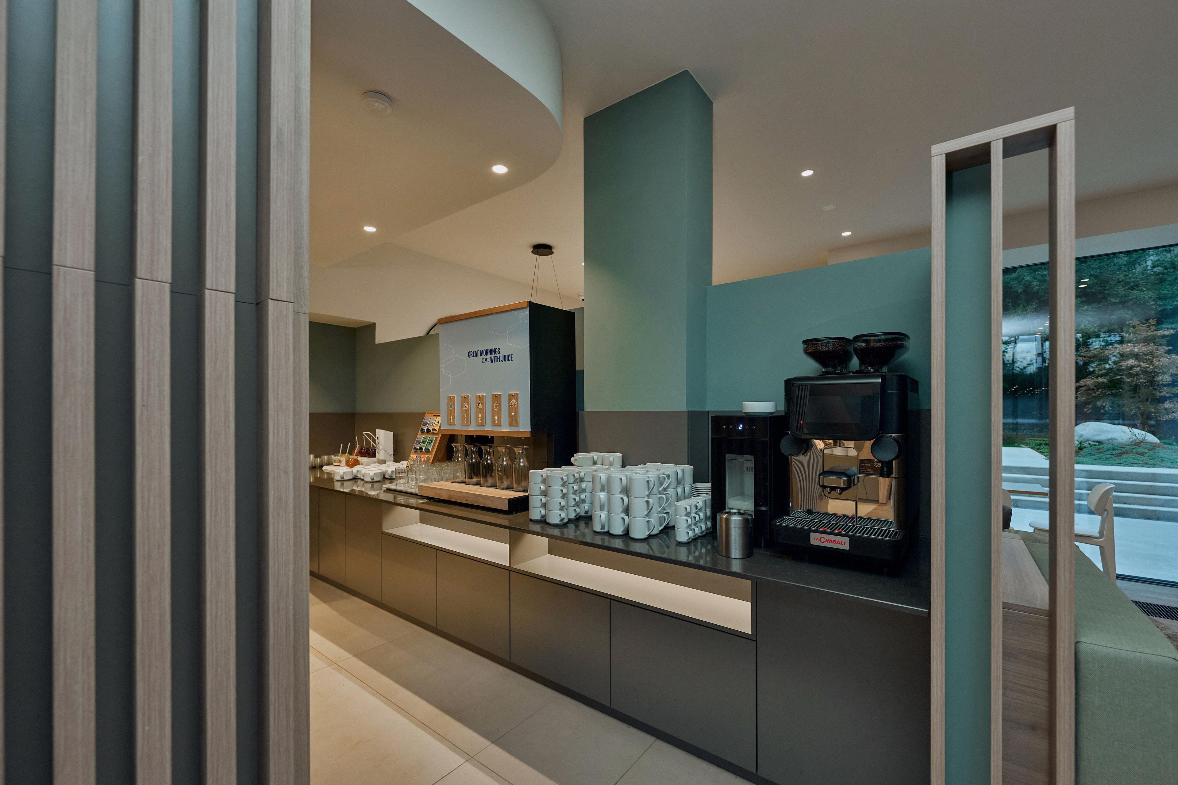 A modern coffee bar with a La Cimbali espresso machine, neatly arranged coffee cups, and a menu board.
