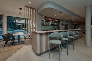 A modern bar area with a curved counter, bar stools, and a glass display of beverages.