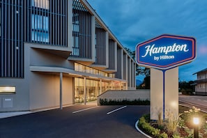 En modern hotellbyggnad med en tydlig skylt som visar att det är ett Hampton by Hilton-hotell.