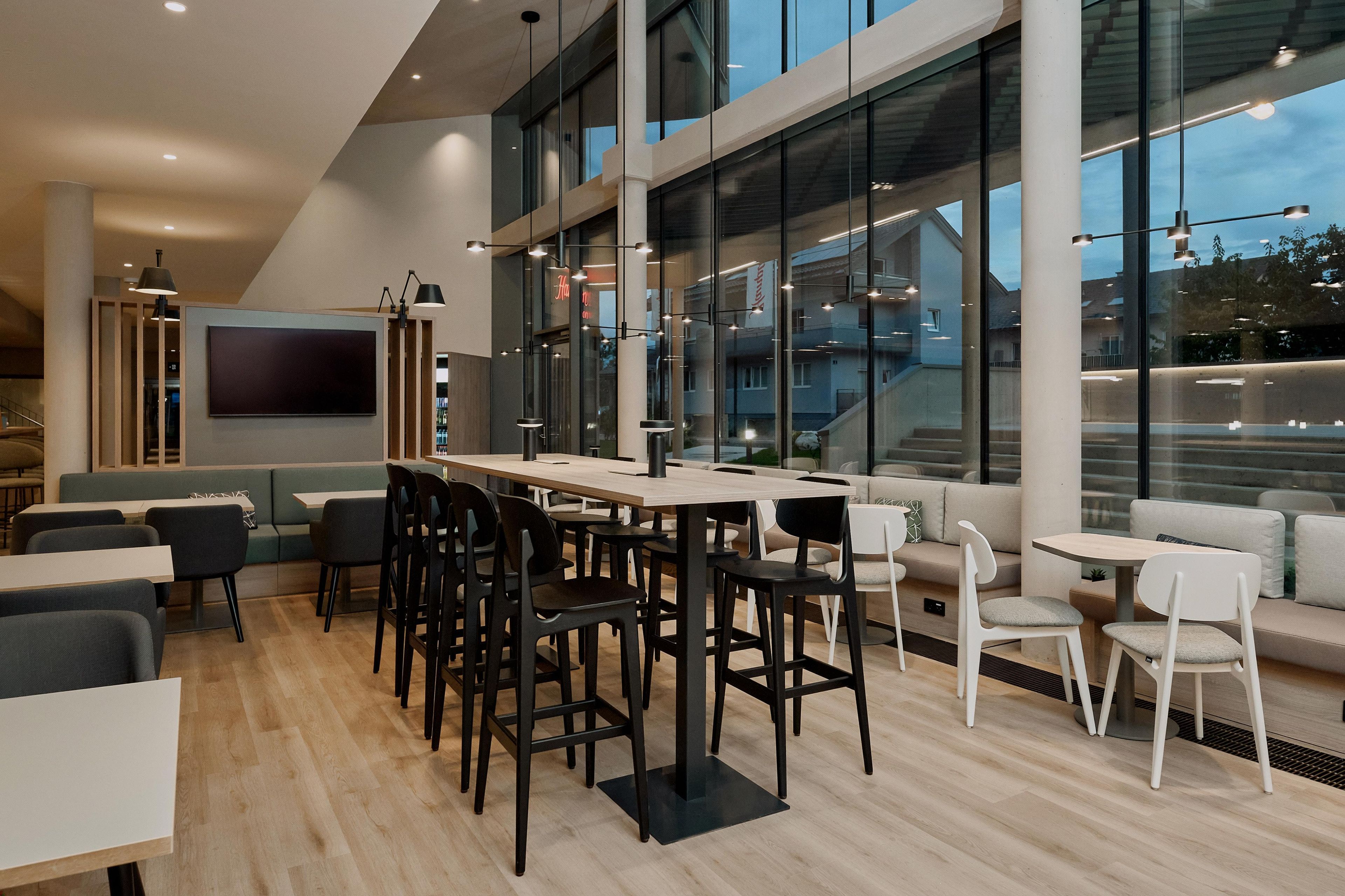 A modern interior with a mix of seating options including tables, chairs, and a sofa area.