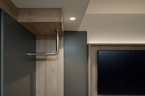 Een moderne badkamer met een houten wastafelmeubel, een handdoekrek en een flatscreen televisie aan de muur.