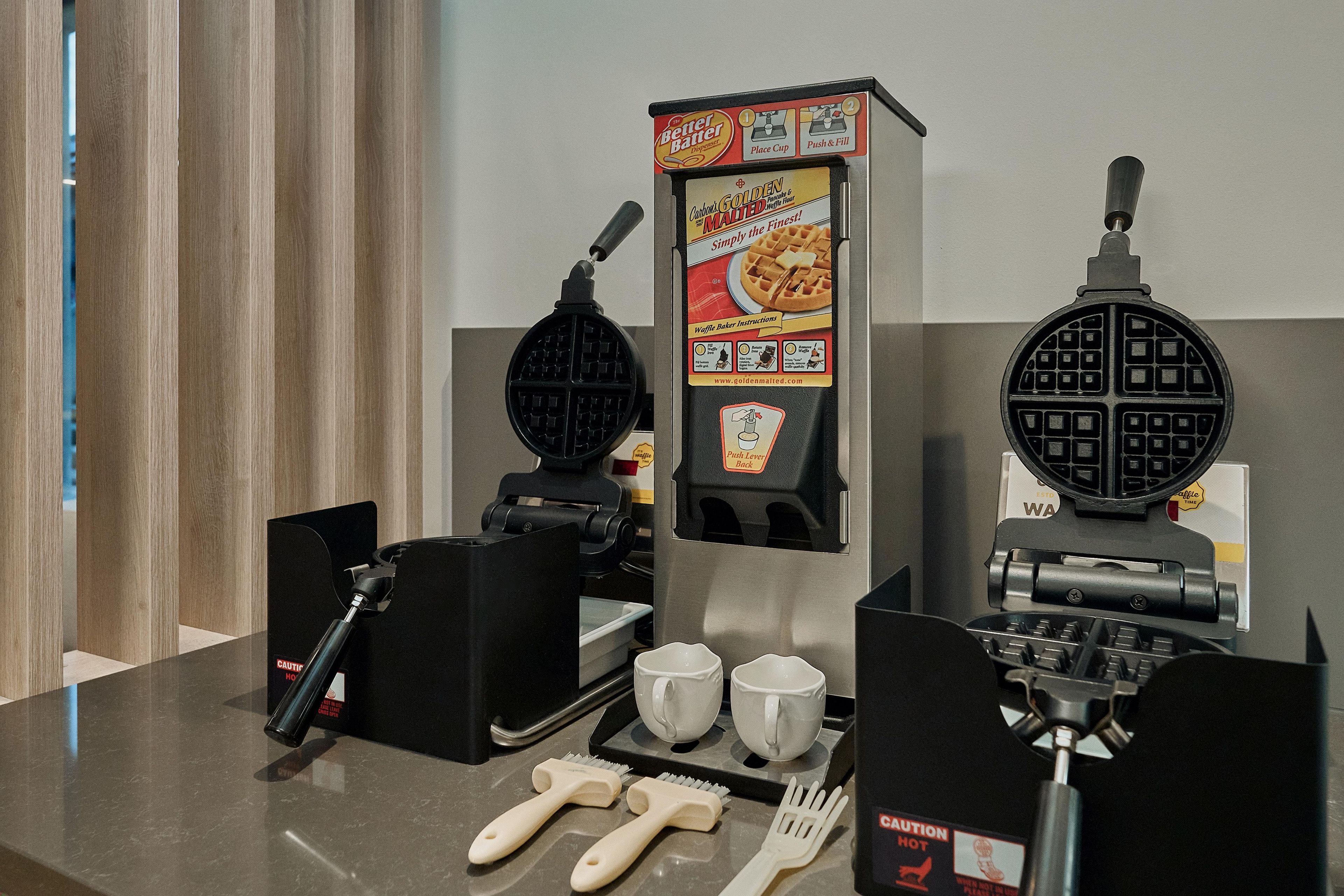 A waffle maker with instructions and a push lever.