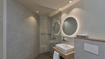 Une salle de bain moderne avec une douche à parois de verre, un lavabo avec un meuble-vasque en bois et deux miroirs fixés au mur.