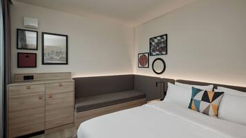 Habitación de hotel con cama, cómoda y zona de estar.