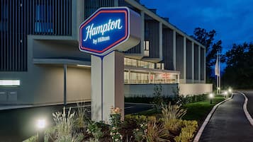 Ein Hotelschild mit dem Schriftzug 'Hilton Hampton' und ein modernes Gebäude mit großen Fenstern und einem Flachdach.