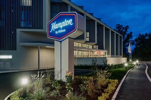 Señal de hotel con el nombre 'Hilton Hampton' y un edificio moderno con ventanas grandes y techo plano.