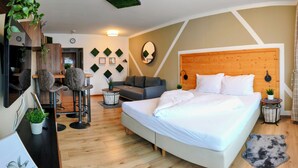 Une chambre d’hôtel moderne avec un grand lit, un canapé, une petite table et un miroir.