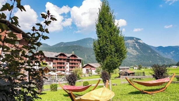 Un hôtel doté d’une pelouse verdoyante, de hamacs et offrant une vue sur les montagnes.