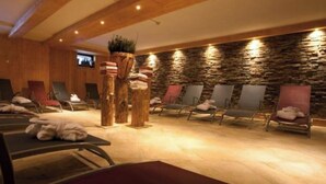 Une salle de spa dotée de plusieurs tables de massage, de piliers en bois et d’un mur en pierre.