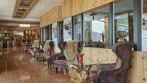 Un hall d’entrée avec des boiseries, une table basse en verre et des fauteuils en cuir.