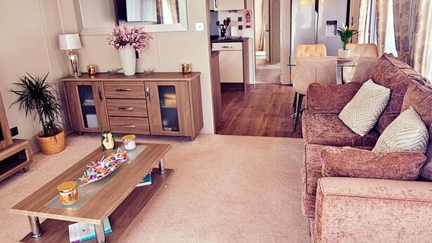 Una sala de estar con una mesa de centro de madera, un sofá, un armario y una planta en maceta.