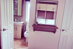 Une salle de bain avec des toilettes, un lavabo et des placards.