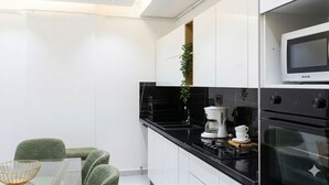 A modern kitchen with white cabinets, a black countertop, a coffee maker, and a microwave. - Charming 2-bedroom Apartment in Tunis With City Views (La Marsa)